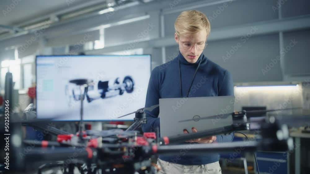 Poster male developer works on engineering project, code at laptop and look at drone at modern office. empo
