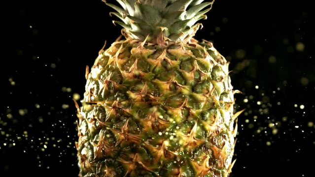 Half Pineapple falling and splashing on black background. Food levitation concept. Slow Motion