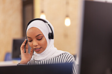 African american muslim girl with hijab and headset in a modern office. Customer service call center