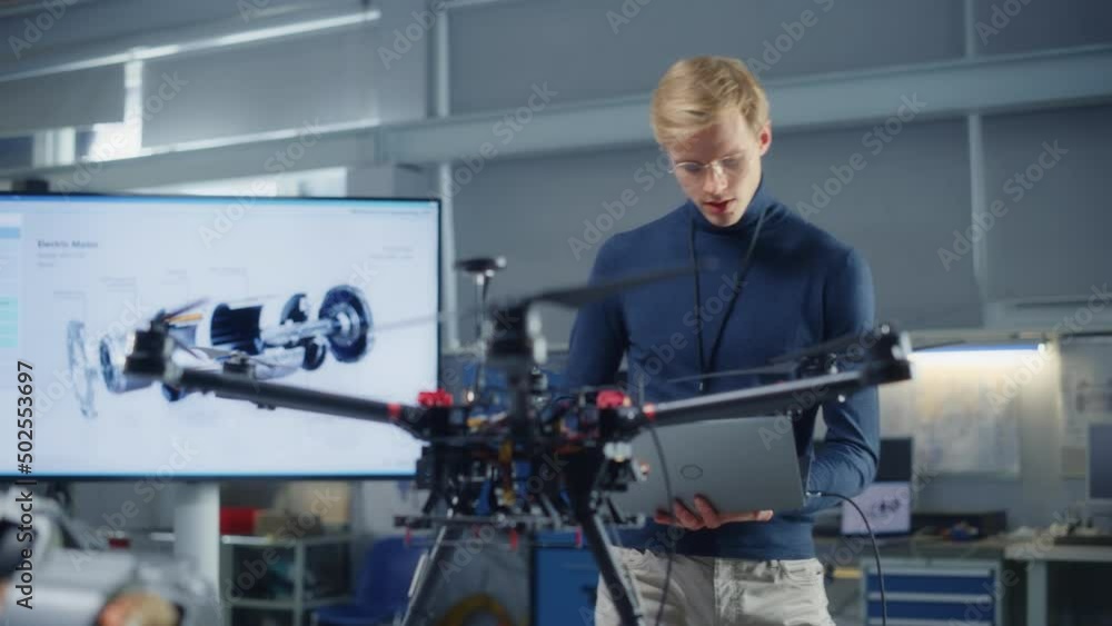 Poster male developer works on engineering project, code at laptop and look at drone at modern office. empo