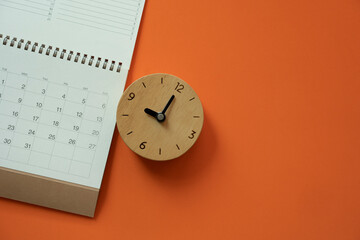 Fototapeta na wymiar close up of calendar and clock on the orange table background, planning for business meeting or travel planning concept