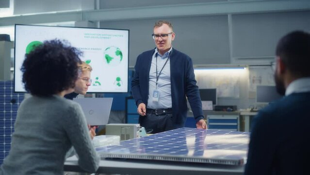 Team Meeting of Renewable Energy Engineers Working on an Innovative More Efficient Solar Panel Battery Concept. Group of Specialists Gathered Around Table, Solving Problems. Bright Research Facility