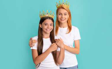 Happy woman mother hug daughter child wearing crowns blue background, prom © Olena