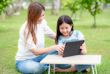 Fototapeta premium A mother is teaching her daughter online on a digital tablet or watching a video clip on a tablet together.