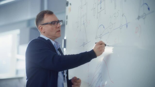 Teacher Talk to Students and Use Chalkboard at University Lecture Class. Smart man Draw Formulas and Schemes at Seminar. Genius Solves Problems Concept