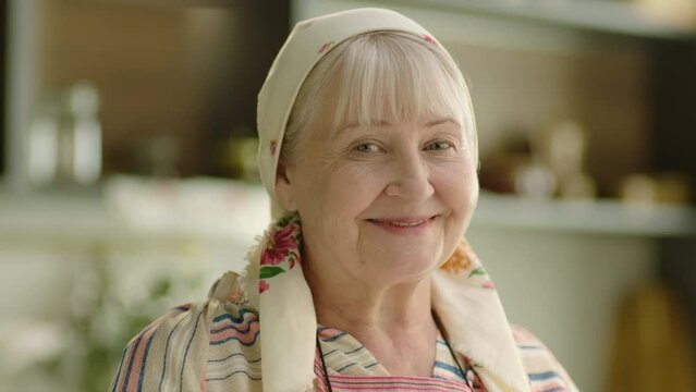Close up portrait of smiling senior woman babushka wearing headscarf