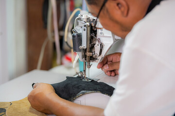 Working process of leather craftsman. Tanner or skinner sews leather on a special sewing machine,...