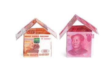 Money houses made of rubles and yuan, isolated on a white background