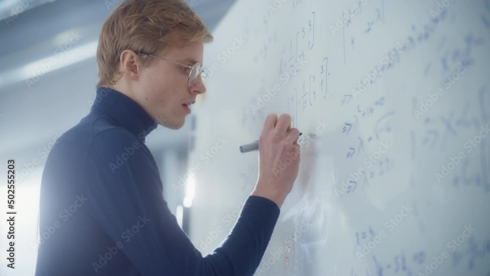 Poster young male scientist write formulas on whiteboard. he solving scientific problems in bright modern h