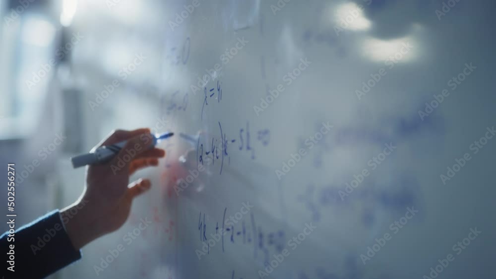 Poster Man Draws Charts and Write Mathematical Formulas on a Whiteboard with Blue Marker Pen. Science and Education Concept. Macro Follow Shot