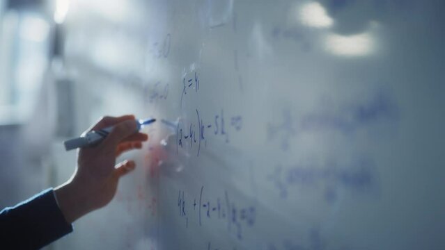 Man Draws Charts and Write Mathematical Formulas on a Whiteboard with Blue Marker Pen. Science and Education Concept. Macro Follow Shot
