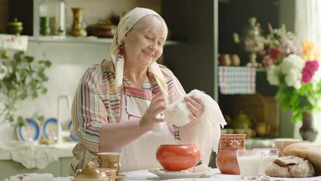 Babushka senior woman cooking cottage cheese in country 