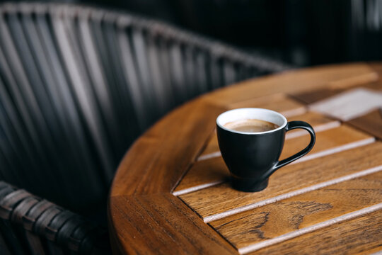 cup of espresso coffee on wooden table on a terrace.