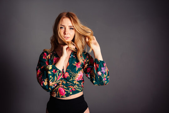 Girl plays with her hair and looks at the camera on a gray background