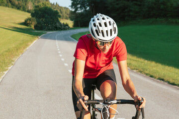 Naklejka premium Young Caucasian female bicyclist in speed sprint position on the bike during fast road cycling race, front view.