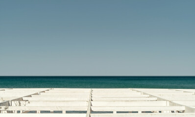 Blurred blue sky and sea, old pier against the background of the sea, selective focus on the deck, bright sunny day. Beach holiday idea at sea, banner idea