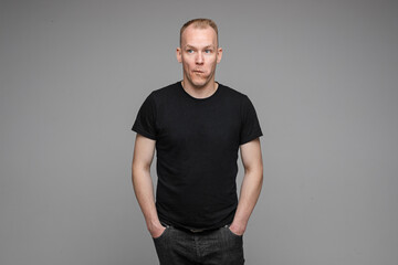 Obraz premium handsome man with short fair hair keeps his hands in the pockets of his black jeans