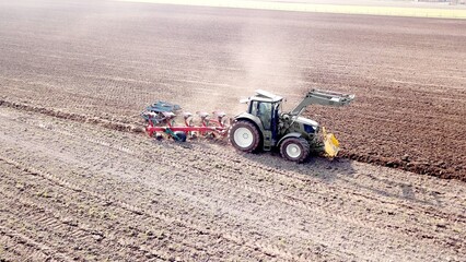 Tractor with plow prepares field for sowing after winter, dust, drought, drought, supply, food, crisis, bird's eye view