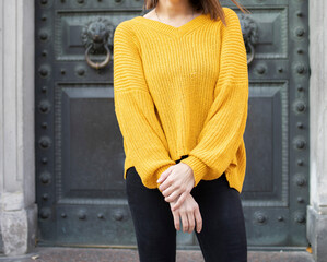 girl in a yellow sweater and jeans, on a city street. Fashionable, bright, casual look. The effect of color on mood