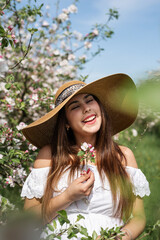 Young caucasian woman enjoying the flowering of an apple trees