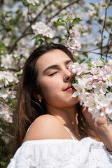 Young caucasian woman enjoying the flowering of an apple trees