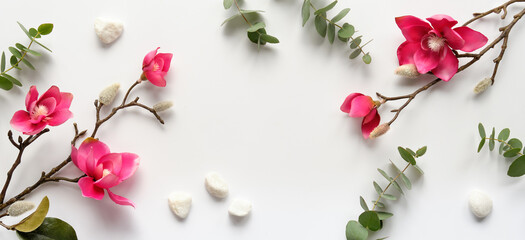 Pink magnolia flowers on twigs, fresh eucalyptus leaves. Blank pink card with grey envelope. Wood word love. Copy-space, place for greeting text. Chinese new year. Top view, off white background.