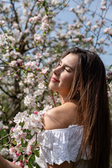 Fototapeta premium Young caucasian woman enjoying the flowering of an apple trees