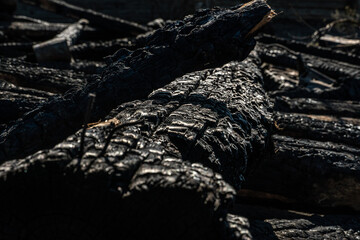 A wooden house in the village burned down because of a forest fire. Charred boards and various things lie on the ground, covered with ash and smoke.