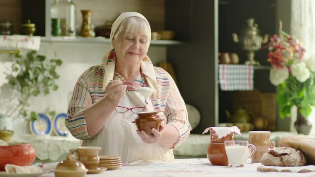 Senior woman wearing headscarf cooking sour cream in country