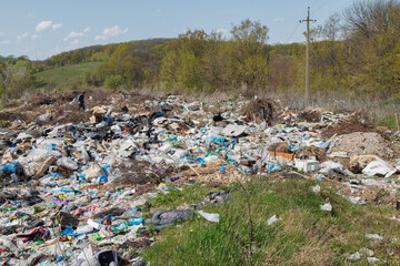 A view of the landfill. Garbage dump. A pile of plastic rubbish, food waste and other rubbish. Pollution concept. A sea of garbage starts to invade and destroy a beautiful countryside scenery