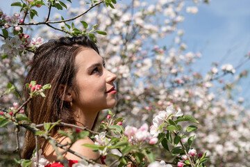 Fototapeta premium Young caucasian woman enjoying the flowering of an apple trees