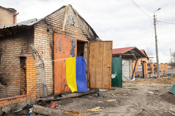 Shelled private house with the flag of Ukraine after the attack of the Russian army. The concept of the country and people cannot be defeated
