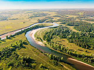 Fototapeta na wymiar Aerial top view of a peaceful river valley among green plain. Summer scene and eco environment.