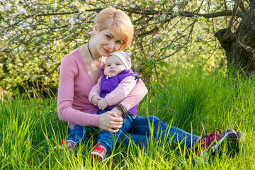 Beautiful girl in the arms of a child girl in a blooming park