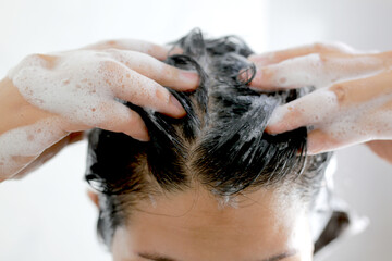 Woman is washing her hair with shampoo - obrazy, fototapety, plakaty