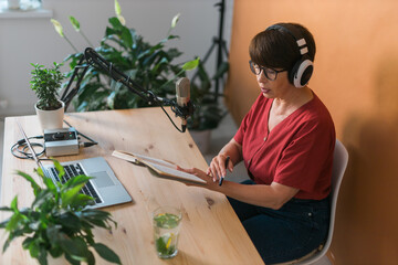 Middle-aged woman radio host making podcast recording for online show - broadcast and dj concept