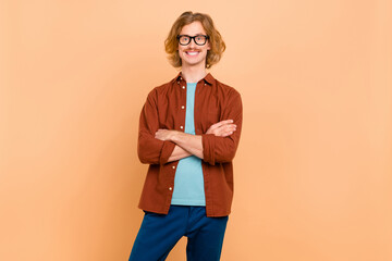 Portrait of attractive cheerful intellectual content red-haired guy folded arms isolated over beige...