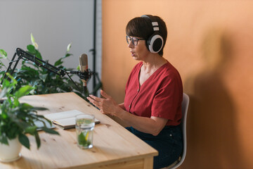 Middle-aged female radio presenter talking into the microphone and reading news - radio broadcast...