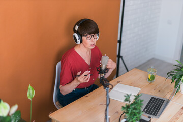 Middle-aged female radio presenter talking into the microphone and reading news - radio broadcast...