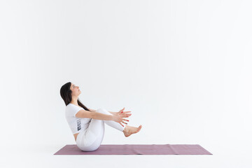 a beautiful young girl with dark hair stands in the pose of Paripurna Navasana on a white background. Yoga class