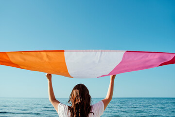 waves a lesbian pride flag in front of the ocean