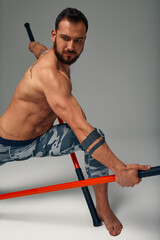 A ninja man holds on to a fighting stick and attacks close-up on gray studio background