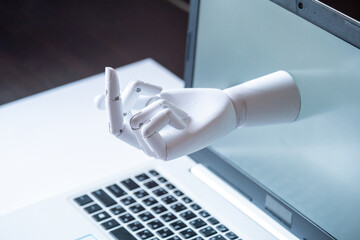 a robot hand with an indecent gesture is visible from the computer monitor. the concept of...