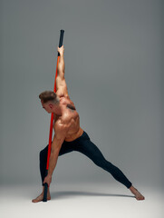 A fighter shirtless in black shorts, stands in a fighting artificially pose and holds a fight stick...