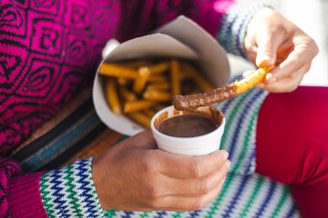 Close-up of a woman dipping a Churro in hot chocolate 
