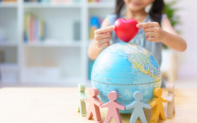 Unidentified little girl's hands place the heart on globe around with people model, concept of...