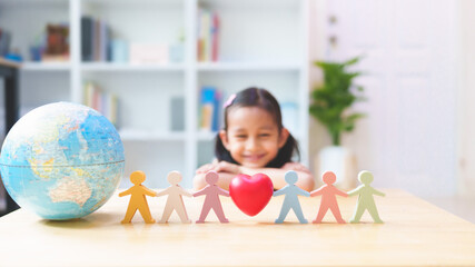 Blurred little girl smiling behind the people, heart, globe model play toys, concept of diversity,...
