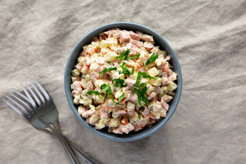 Homemade Olivier salad in a Bowl on a white wooden background, top view. Flat lay, overhead, from above.