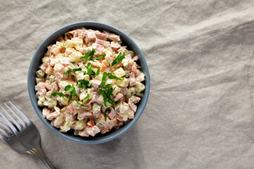 Homemade Olivier salad in a Bowl on a white wooden background, top view. Flat lay, overhead, from above. Copy space.