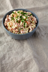 Homemade Olivier salad in a Bowl on a white wooden background, side view. Space for text.